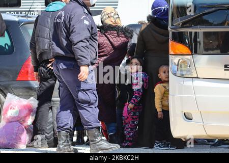 Ein kleines Mädchen starrt einen Polizisten mit einer Maske an. Neue Flüchtlingslager und Flüchtlingslager in Griechenland im Raum Kleidi in der Nähe des Dorfes Promahonas in der Region Serres, an der griechisch-bulgarischen Grenze, erhalten die erste Welle von Menschen, Asylbewerbern, die nach dem 1.. März 2020 nach Griechenland einreisen, wo das Land die Annahme von Asylanträgen eingestellt hat. Neuankömmlinge kommen von den Inseln Lesvos, Samos und Chios und wurden mit der Fähre nach Kavala und dann mit dem Bus nach Kleidi gebracht, um sie aufzunehmen, zu fotografieren, vorübergehend zu beherbergen und dann in ihr Herkunftsland wie Afghanistan, Paki, abzuschieben Stockfoto