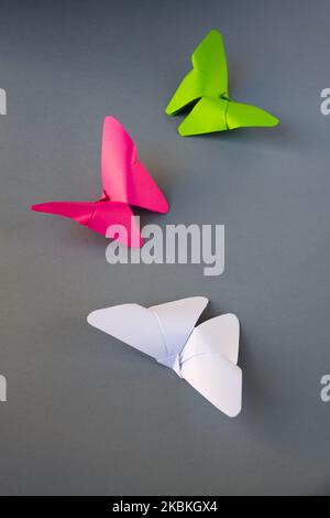 Grün, rosa und weiß Papier Schmetterling Origami isoliert auf einem weißen grauen Hintergrund. Stockfoto