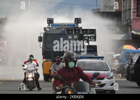 Der Motorradfahrer überquert die rechte Seite des Polizeikonvois und gibt den Menschen auf dem traditionellen Markt, Palu City, Zentral-Sulawesi, Ratschläge, sich immer von anderen zu distanzieren, gemäß den Anweisungen des indonesischen Präsidenten am Donnerstag, dem 26. März 2020. Das Spritzen auf traditionellen Märkten in verschiedenen Provinzen Indonesiens wird routinemäßig von der Regierung durchgeführt, um die Ausbreitung des Corona-Virus zu unterdrücken. (Foto von Faldi Muhammad/NurPhoto) Stockfoto