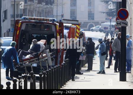 Feuerwehrleute in Paris mit Coronavirus-Schutz werfen einen kranken Patienten auf die Straße vor dem Eingang der Notaufnahme des Tenon-Krankenhauses. Überlastung und Überbelegung in den Notaufnahmen des Krankenhauses von Thenon in Paris, Frankreich, am 27. März 2020. (Foto von Mehdi Taamallah/NurPhoto) Stockfoto