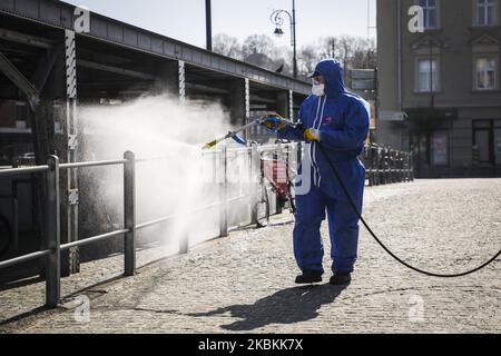 Ein Mitarbeiter der Municipal Cleaning Company (MPO) verwendet einen Druckschlauch, um Bus- und Straßenbahnhaltestellen sowie öffentliche Plätze mit Reinigungsmitteln gegen die Ausbreitung des Coronavirus zu desinfizieren. Krakau, Polen, am 27. März 2020. Die polnische Regierung beschloss, im ganzen Land neue Beschränkungen einzuführen, wie beispielsweise Vorschriften, die das Verlassen der Heimat verhindern, sofern dies nicht gerechtfertigt ist. (Foto von Beata Zawrzel/NurPhoto) Stockfoto