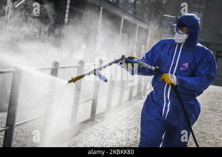 Ein Mitarbeiter der Municipal Cleaning Company (MPO) verwendet einen Druckschlauch, um Bus- und Straßenbahnhaltestellen sowie öffentliche Plätze mit Reinigungsmitteln gegen die Ausbreitung des Coronavirus zu desinfizieren. Krakau, Polen, am 27. März 2020. Die polnische Regierung beschloss, im ganzen Land neue Beschränkungen einzuführen, wie beispielsweise Vorschriften, die das Verlassen der Heimat verhindern, sofern dies nicht gerechtfertigt ist. (Foto von Beata Zawrzel/NurPhoto) Stockfoto