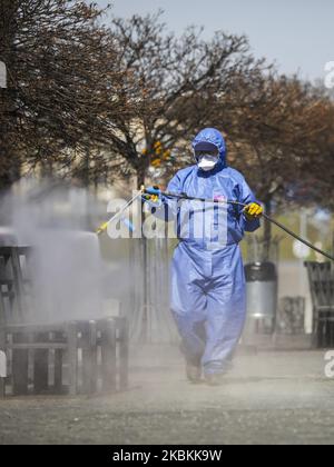 Ein Mitarbeiter der Municipal Cleaning Company (MPO) verwendet einen Druckschlauch, um Bus- und Straßenbahnhaltestellen sowie öffentliche Plätze mit Reinigungsmitteln gegen die Ausbreitung des Coronavirus zu desinfizieren. Krakau, Polen, am 27. März 2020. Die polnische Regierung beschloss, im ganzen Land neue Beschränkungen einzuführen, wie beispielsweise Vorschriften, die das Verlassen der Heimat verhindern, sofern dies nicht gerechtfertigt ist. (Foto von Beata Zawrzel/NurPhoto) Stockfoto