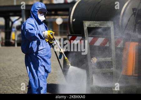 Ein Mitarbeiter der Municipal Cleaning Company (MPO) verwendet einen Druckschlauch, um Bus- und Straßenbahnhaltestellen sowie öffentliche Plätze mit Reinigungsmitteln gegen die Ausbreitung des Coronavirus zu desinfizieren. Krakau, Polen, am 27. März 2020. Die polnische Regierung beschloss, im ganzen Land neue Beschränkungen einzuführen, wie beispielsweise Vorschriften, die das Verlassen der Heimat verhindern, sofern dies nicht gerechtfertigt ist. (Foto von Beata Zawrzel/NurPhoto) Stockfoto