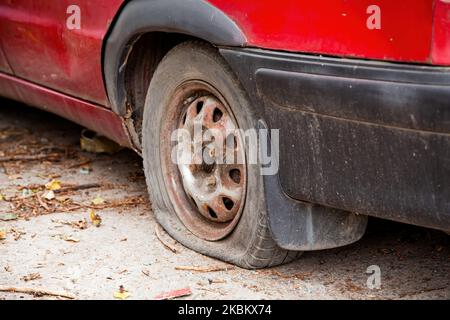 Ein Platten Reifen auf einem Auto. Flacher Autoreifen aus nächster Nähe, durchbrochenes Rad. Rotes Auto mit kaputtem Reifen Stockfoto