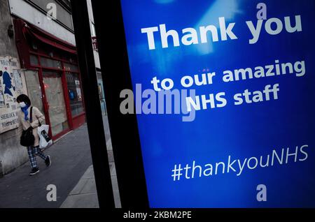 Eine Frau, die eine Maske trägt, geht an einer Dankesbotschaft an die Mitarbeiter des National Health Service (NHS) vorbei, die am 6. April 2020 auf dem digitalen Werbebildschirm einer Bushaltestelle in der Baker Street in London, England, angezeigt wird. Großbritannien begann heute mit der dritten Woche der Blockierung des Coronavirus, wobei die Maßnahmen voraussichtlich verlängert werden, sobald die anfängliche dreiwöchige Sperrfrist erreicht ist. Während das Land weiterhin auf seinen „Höhepunkt“ der Epidemie wartet, zeigen heute veröffentlichte Zahlen, dass insgesamt 51.608 Menschen im Vereinigten Königreich nun positiv auf das Covid-19-Coronavirus getestet wurden, 3.802 mehr als gestern, mit 5.373 Stockfoto