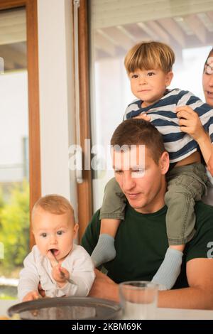 Die schöne Mutter bringt ihren Sohn zu seinem Vater zurück, während der Vater das Baby hält Stockfoto
