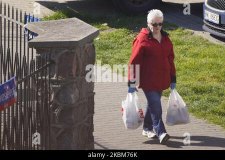 Am 9. April 2020 wird in Warschau, Polen, eine Frau gesehen, die Einkaufstaschen mit Lebensmitteln trägt, während sie Handschuhe trägt. Die polnische Regierung hat am Donnerstag angekündigt, dass sie die Beschränkungen für den Umzug im Freien für die Öffentlichkeit weiter erhöhen wird. (Foto von Jaap Arriens/NurPhoto) Stockfoto