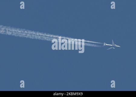 Ein Flugzeug, das am 11. April 2020 im klaren, blauen, fast sommerlichen Himmel über Thessaloniki, Griechenland fliegt. Das Flugzeug hinterlässt Kondensstreifen oder Chemtrails, also Dampf aus Kondensation. Überflieger sind am Himmel selten, weil viele Regierungen den Ländern ein Verkehrsverbot aufgrund der Coronavirus-Covid-19-Pandemie auferlegt haben. Das spezifische Flugzeug ist ein kommerzieller Jet, eine Boeing 777 von Privilege Style Airline Carrier mit der Registrierung EC-MUA. (Foto von Nicolas Economou/NurPhoto) Stockfoto