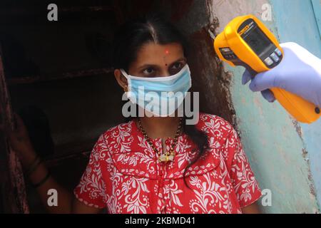 Eine Frau, die eine Gesichtsmaske trägt, lässt sich am 14. April 2020 im Slum von Dharavi in Mumbai, Indien, auf ihre Körpertemperatur überprüfen. Indien befindet sich weiterhin im landesweiten Sperrgebiet, um die Ausbreitung der Coronavirus-Pandemie (COVID-19) zu kontrollieren. (Foto von Himanshu Bhatt/NurPhoto) Stockfoto