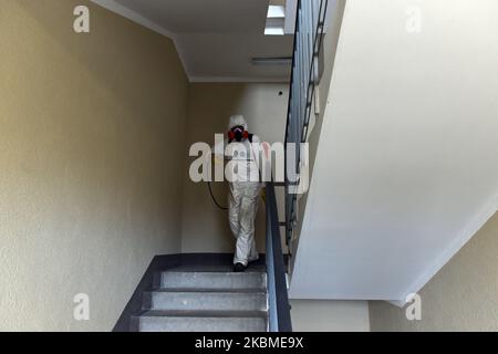 Ein Mitarbeiter der öffentlichen Versorgungsunternehmen, der chemische Schutzkleidung trägt, während er eine Eingangshalle eines Wohnhauses desinfiziert, um die Verbreitung von Covid-19 in Sankt Petersburg, Russland, am 13. April 2020 zu verhindern. (Foto von Sergey Nikolaev/NurPhoto) Stockfoto