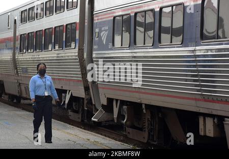 Ein Amtrak-Mitarbeiter mit einer schützenden Gesichtsmaske läuft an einem fast leeren, nach Süden fahrenden Amtrak-Zug entlang, der am 15. April 2020 in Orlando, Florida, eintrifft. Die COVID-19-Pandemie hat dazu geführt, dass Amtrak auf vielen Strecken einen reduzierten Zeitplan einhält, den Dienst auf anderen Strecken aussetzt und einige Stationen vorübergehend schließt. (Foto von Paul Hennessy/NurPhoto) Stockfoto