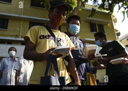 Menschen, die Schutzmasken tragen, während sie Lebensmittel zur freien Verfügung erhalten und sich aufgrund der Ausbreitung des Ausbruchs der Coronavirus-Krankheit (COVID-19) am 18. April 2020 in Bangkok, Thailand, an die sozialen Distanzierungsregeln halten. (Foto von Anusak Laowias/NurPhoto) Stockfoto