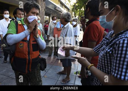 Menschen, die Schutzmasken tragen, als sie Geldgeschenke erhalten und sich aufgrund der Ausbreitung des Ausbruchs der Coronavirus-Krankheit (COVID-19) am 18. April 2020 in Bangkok, Thailand, an die sozialen Distanzierungsregeln halten. (Foto von Anusak Laowias/NurPhoto) Stockfoto