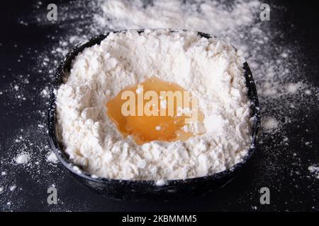 In der Nahaufnahme wird dem Weißmehl Ei hinzugefügt Stockfoto