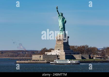 Freiheitsstatue, die während eines wolkenlosen Tages mit Touristen und Besuchern von Liberty Island Manhattan, New York City, USA, von einer Fähre im Meer aus gesehen wird. Die ikonische Kupferstatue erreicht 93m über dem Meer und wurde am 28. Oktober 1886 eingeweiht. Es wurde vom französischen Bildhauer Frédéric Auguste Bartholdi entworfen und sein Metallrahmen wurde von Gustave Eiffel gebaut, die Skulptur war ein Geschenk des französischen Volkes. Heute ist es eine beliebte Touristenattraktion, ein Reiseziel, Wahrzeichen von NYC und den USA, eines der bekanntesten Symbole der Welt. Die Statue ist eine Figur von Stockfoto