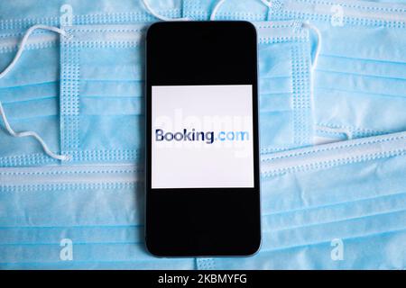 Das Booking.com-Logo wird auf einem Mobiltelefon-Bildschirm angezeigt, der auf einem Hintergrund mit chirurgischen Masken fotografiert wurde, um ein Illustrationsfoto während der Ausbreitung des Coronavirus zu machen. Krakau, Polen, am 26. April 2020. (Fotoillustration von Beata Zawrzel/NurPhoto) Stockfoto