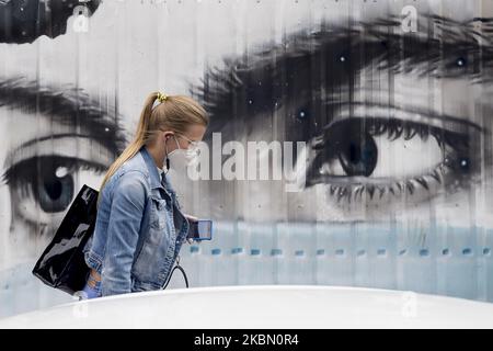 Eine Frau geht vor Graffiti in Bezug auf die Verwendung von chirurgischen Masken während der Coronavirus - Covid19 Krise in Barcelona, Katalonien, Spanien, am 27. April 2020. (Foto von Miquel Llop/NurPhoto) Stockfoto