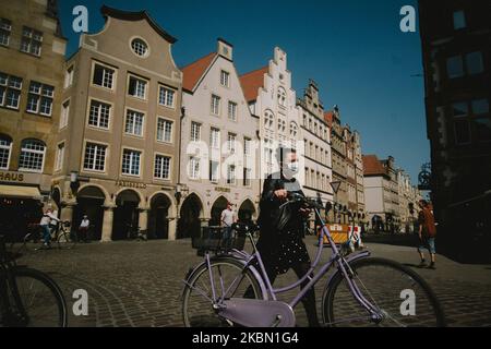 Eine Frau mit Gesichtsmaske geht am domplatz von Münster vorbei, da Deutschland am 27. April 2020 während des Coronavirus-Notfalls das Tragen einer Gesichtsmaske im Zug, Bus und auch in Geschäften obligatorisch macht. (Foto von Ying Tang/NurPhoto) Stockfoto