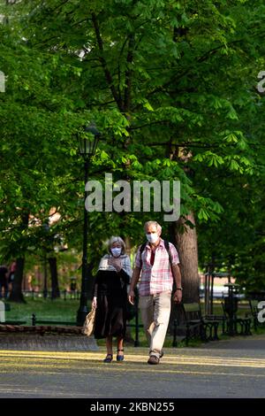 Ein älteres Paar mit Schutzmaske genießt einen Spaziergang im öffentlichen Park Planty in Krakau, Polen an einem sonnigen Frühlingstag am 28. April 2020. Nach einigen Wochen strenger Absperrung und sozialer Distanzierung durch Coronavirus-Ausbreitung dürfen sich die Polen wieder im freien Raum entspannen, müssen aber in der Öffentlichkeit stets Abstand halten und Schutzmasken tragen. (Foto von Dominika Zarzycka/NurPhoto) Stockfoto