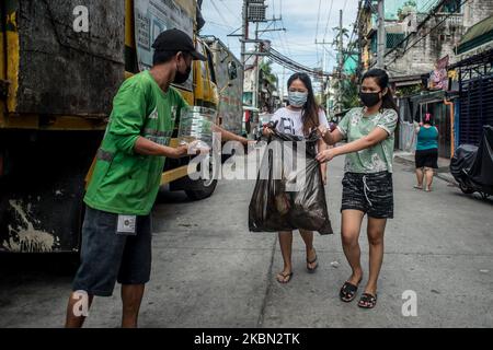 Die Bewohner bringen am 29. April 2020 ihren Hausmüll für Müllsammler in Quezon City, Philippinen, zur Abholung. Auch als Frontliner gefeiert, arbeiten Müllsammler trotz der gesundheitlichen Risiken und des Mangels an persönlicher Schutzausrüstung (PSA) weiterhin eng mit unterschiedlichen Abfällen in Kontakt. Auf den Philippinen gab es bisher insgesamt 8.212 COVID-19-Fälle, 558 Todesfälle und 1.023 Genesungen.(Foto: Lisa Marie David/NurPhoto) Stockfoto