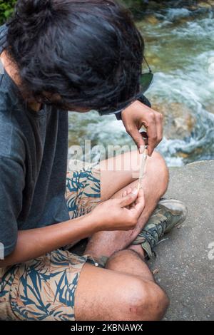 Juli 14. 2022, Himachal Pradesh Indien.. Eine Seitenpose eines jungen Mannes mit einem Mann, der ein Unkrautgelenk in den Hügeln des Himalaya rollt. Stockfoto