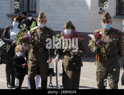 Am 09. Mai 2020 tragen Menschen Blumen zum Denkmal des ewigen Ruhms auf dem Grab des unbekannten Soldaten, während der Feier des Sieges inmitten des Covid-19-Coronavirus-Ausbruchs in Kiew, Ukraine. Die Ukrainer gedenken des 75.. Jahrestages des Sieges über Nazi-Deutschland im Zweiten Weltkrieg. (Foto von STR/NurPhoto) Stockfoto