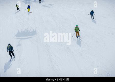 Skifahrer, die auf der Skipiste La Plagne das Pistengebiet hinunterfahren Stockfoto