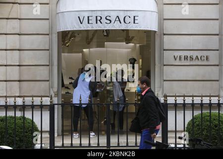 Ein Mann geht auf die Straße, während zwei Arbeiter am 11. Mai 2020 die Türen des Versace-Ladens in der Avenue de Montaigne in Paris putzen, Am ersten Tag einer teilweisen Aufhebung einer fast zweimonatigen Sperre, die in Frankreich verhängt wurde, um die Ausbreitung der durch das neue Coronavirus (COVID-19) verursachten Pandemie zu stoppen. (Foto von Mehdi Taamallah/NurPhoto) Stockfoto