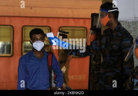 Ein Sri-lankischer Soldat führt eine Temperaturkontrolle an einem Pendler durch, der zur Arbeit in Colombo, Sri Lanka, eintraf. 11 Mai 2020. Tausende von Sri-lankischen soldiersÂ wurden von der Regierung Sri Lankas eingesetzt, seit im März die Sperrstunde im ganzen Land nach assistÂ verhängt wurde, um die Ausbreitung des Covid-19-Virus in Sri Lanka zu minimieren. Â die Regierung Sri Lankas unter der Leitung von Präsident Gotabaya RajapaksaÂ hat den Großteil des Staates und wieder aufgenommen Dienstleistungen des privaten Sektors am Montag (11) in ColomboÂ inmitten der Ausgangssperre . Laut dem Lagebericht Covid-19 (11. Mai 2020) der Epidemiologischen Abteilung ofÂ in Sri Lanka Stockfoto