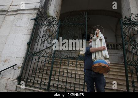 Ein Assistent der Kirche von Penha de FranÃ§A trägt das Bild der Jungfrau Maria, um sich auf die Pilgerfahrt in den verschiedenen Straßen von Lissabon vorzubereiten. 12. Mai 2020. Auf Vorschlag der portugiesischen Regierung, eine soziale Distanz zu wahren, um die Ausbreitung von COVID-19 zu vermeiden, wurden viele soziale Aktivitäten gestrichen und andere in ihrer Programmplanung geändert, Das ist der Fall der religiösen Feierlichkeiten zu Ehren der Jungfrau von Fatima, deren zentraler Tag der 13. Mai ist, und dass die Behörden der katholischen Kirche beschlossen haben, sie als Pilgerfahrt "ohne Pilger" zu feiern, die aus besteht Stockfoto