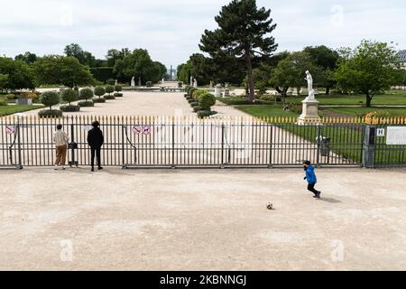 Ein Kind spielt vor dem geschlossenen Eingang zum Garten der Tuilerien Ball, während ein Paar am Dienstag, dem 12. Mai 2020, in Paris, den Tag nach dem Ende der Sperre in Frankreich aufgrund der COVID-19-Pandemie, durch das Tor schaut. Wo die Pariser beginnen, ihre Heimat zu verlassen, um die Freiheit zu genießen oder wieder zur Arbeit zu gehen. (Foto von Samuel Boivin/NurPhoto) Stockfoto