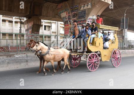 Personen mit Gesichtsmast, die während einer landesweiten Sperre als vorbeugende Maßnahme gegen das COVID-19-Coronavirus mit dem Pferdewagen unterwegs waren, am 13. Mai 2020 in Dhaka (Foto: Mamunur Rashid/NurPhoto) Stockfoto