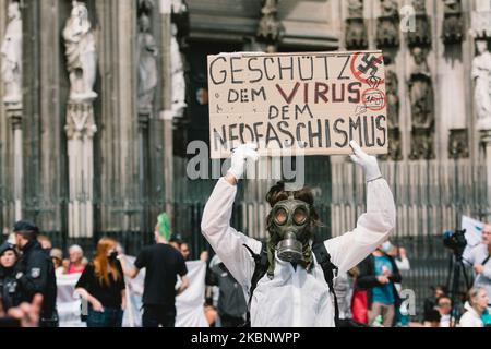 Ein Mann mit Gasmaske und Schutzanzügen hält ein Plakat mit dem Namen „Protect the Virus of Nazi“, das während der Kundgebung gegen die Coronavirus-Politik am 16. Mai 2020 in Köln zu sehen ist. (Foto von Ying Tang/NurPhoto) Stockfoto