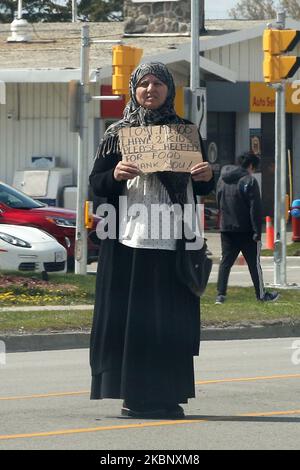 Eine muslimische Frau, die am 16. Mai 2020 mit einem Schild steht und die Autofahrer auffordert, ihr an einer belebten Straße in Richmond Hill, Ontario, Kanada, ihren Ersatzwechsel zu geben. (Foto von Creative Touch Imaging Ltd./NurPhoto) Stockfoto