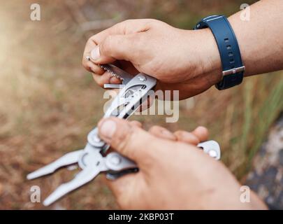 Menschenhände verwenden Mehrzweckmesser für Camping, Outdoor-Überleben und Abenteuer in Park, Wald und Pfadfinder Wandern. Scharfes Taschenwerkzeug, praktisches Accessoire Stockfoto