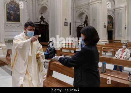 Der Priester mit Maske und Handschuhen bereitet sich auf die Kommunion auf den Händen der Gläubigen mit Handschuhen bedeckt, in Carolei (CS) am 18. Mai 2020. Am 18. Mai 2020 werden in Italien wieder Kirchen eröffnet. Nach mehr als zwei Monaten der Sperrung hat die Regierung grünes Licht für die „Phase 2“ oder die Wiedereröffnung von Kirchen und Geschäften gegeben. (Foto von Andrea Pirri/NurPhoto) Stockfoto