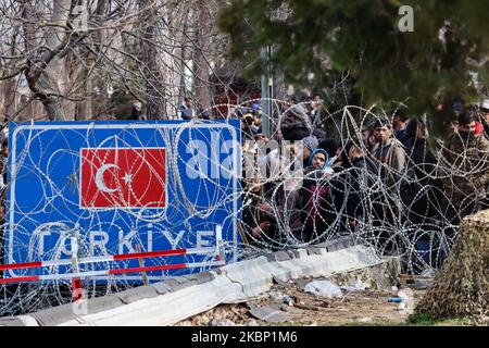 Ein Schild mit der türkischen Flagge und Migranten, die während des Protestes illegal nach Griechenland einreisen wollen. Migrantengruppen am Grenzübergang Pazarkule und Kastanies, bestehend hauptsächlich aus Menschen aus Afghanistan, sind zwischen der griechischen und der türkischen Grenze gestrandet, am Grenzübergang Kastanies in Griechenland und am Grenzübergang Pazarkule in der Nähe von Edirne in der Türkei in der neutralen Zone. Die Migranten und Flüchtlinge versuchen, über Griechenland nach Europa einzureisen. Asylbewerber protestieren und werfen Steine und Tränengas auf griechische Sicherheitskräfte, Polizei und Armee, die mit Tränengas und Blitzgranaten reagieren. . Die Türkei kündigte an, dass sie Bor öffnen würde Stockfoto