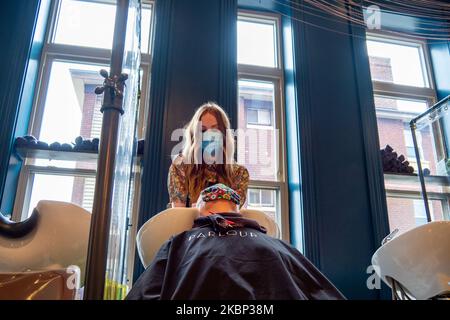 Die Kosmetikerin Lillian Kappa spült die Haare eines Kunden im Salon zwischen den Vinylsieben, um seine Kunden vor einer möglichen COVID-19-Übertragung zu schützen, da Schönheitssalons, Friseurläden und Spas nach der Coronavirus COVID-19-Pandemie am Mittwoch, den 20. Mai 2020 in Cincinnati, Ohio, Usa. (Foto von Jason Whitman/NurPhoto) Stockfoto