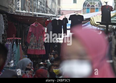 Die Bewohner drängen den Markt, um vor dem Eid Al Fitr-Fest neue Kleidung zu kaufen, während die umfangreichen sozialen Einschränkungen während des Coronavirus Covid-19-Ausbruchs am 20. Mai 2020 in Jakarta stattfräulichen. Obwohl die Regierung von Jakarta eine Reihe von Markt- und Handelsgebieten vorübergehend geschlossen hat, verkaufen einige Händler weiterhin auf den Gehwegen und in den örtlichen Dorfgassen, da die Nachfrage nach Kleidung vor dem Eid Al Fitr Fest steigt. (Foto von Aditya Irawan/NurPhoto) Stockfoto