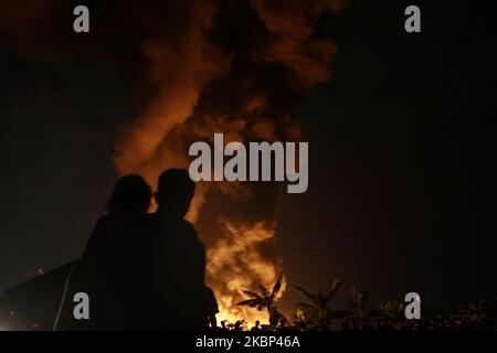 Die Bewohner beobachten die Flammen, wie am 21. Mai 2020 in der Kunststoff-Recycling-Fabrik in Bekasi, Provinz West-Java, Feuer ausbrach. Augenzeugenberichten zufolge kam es aufgrund eines elektrischen Kurzschlusses zu einem Brand, als die Fabrik aufgrund der Einführung einer groß angelegten sozialen Beschränkung im Zuge der Coronavirus-Covid-19-Krise geschlossen wurde. Im Präsidenten wurden keine Todesfälle gemeldet. (Foto von Aditya Irawan/NurPhoto) Stockfoto