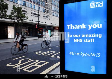 Fahrradfahrer fahren am 21. Mai 2020 an einer Dankesnachricht an den National Health Service (NHS) vorbei, die auf dem digitalen Werbebildschirm einer Bushaltestelle auf einer nahe verlassenen Oxford Street in London, England, angezeigt wird. Es wird angenommen, dass die Coronavirus-Fälle in der gesamten Hauptstadt auf ein sehr niedriges Niveau fallen, wobei diesen Montag überhaupt keiner aufgezeichnet wurde, laut Daten von Public Health England und Medien, die gestern berichteten, dass sechs große Londoner Krankenhäuser in den letzten 48 Stunden keine kovid-19 Todesfälle verzeichnet hatten. Die Zahl der Todesfälle in Großbritannien beläuft sich mittlerweile auf 36.042, was der Tagesgesamtmenge entspricht, die heute Nachmittag von der Dep veröffentlicht wurde Stockfoto