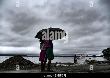 Kinder unter einem Regenschirm am Ufer des Flusses Brahmaputra vor dem Hintergrund dunkler Wolken, die den Himmel an einem regnerischen Tag bedecken, am Samstag, den 23. Mai in Guwahati, Assam, Indien, 2020. (Foto von David Talukdar/NurPhoto) Stockfoto