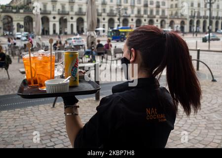 Eine Kellnerin mit Schutzmaske serviert auf der Piazza Vittorio Veneto in Turin, Italien, einen Tisch mit Menschen. Am 23. Mai konnte die Region Piemont die Tischsitze in Cafés und Bars wieder öffnen, solange die Menschen nach mehr als zwei Monaten einer landesweiten Sperre, die die Ausbreitung von COVID-19 eindämmen sollte, soziale Distanzierungen praktizieren. (Foto von Mauro Ujetto/NurPhoto) Stockfoto