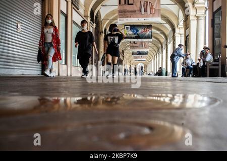 Menschen mit Schutzmaske gehen in der Nähe eines Stiers auf dem Boden, dem Symbol von Turin auf der Piazza San Carlo in Turin, Italien. Am 23. Mai konnte die Region Piemont die Tischsitze in Cafés und Bars wieder öffnen, solange die Menschen nach mehr als zwei Monaten einer landesweiten Sperre, die die Ausbreitung von COVID-19 eindämmen sollte, soziale Distanzierungen praktizieren. (Foto von Mauro Ujetto/NurPhoto) Stockfoto