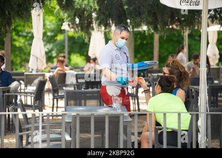 Am 25. Mai desinfiziert ein Kellner auf der Außenterrasse eines Cafés in Madrid, Spanien, eine Tischfläche für junge Kunden. Heute ist der erste Tag von Madrid in der Phase 1 der Enteskalation der Haft, können Menschen auf Terrassen und Terrassen gehen und beginnen, mit Gruppen von mehr als 10 Personen, Parque del Retiro, Madrid zu bleiben. (Foto von Jon Imanol Reino/NurPhoto) Stockfoto