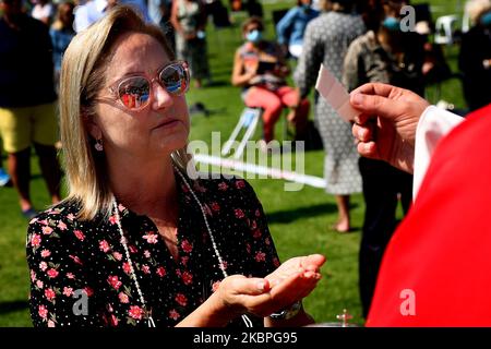 Die Reflexion des Priesters Nuno Coelho wird in der Sonnenbrille eines Gläubigen gesehen, als sie den Gastgeber während einer Freiluftmesse im Hippodrom in Cascais, Portugal, am 31. Mai 2020 inmitten der COVID-19-Pandemie empfängt. Neue Regeln für die Gläubigen und Anpassungen der Kulte wurden von der katholischen Kirche angenommen, um die Kirchen wieder zu öffnen. (Foto von Pedro FiÃºza/NurPhoto) Stockfoto