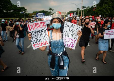 Eine Frau, die ein Plakat mit der Aufschrift „Duterte faschistische Terroristenpuppe Chinas“ und „Black Lives Matter Resist As One“ trägt, schließt sich am 4. Juni 2020 an der Universität der Philippinen in Quezon City, Philippinen, einem Protest gegen das Anti-Terror-Gesetz an. Nach dem vorgeschlagenen Gesetz kann eine Person, die als Terrorist verdächtigt wird, bis zu 24 Tage ohne Haftbefehl festgehalten, unter Überwachung gestellt und zu lebenslanger Haft verurteilt werden. Der Entwurf wurde gestern, am 3. Juni, vom Repräsentantenhaus in dritter und letzter Lesung angenommen. ' Passiert einen Polizisten während eines Stockfoto