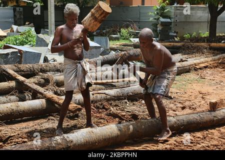 Arbeiter benutzen eine Axt, einen Meißel, einen Keil und einen Holzhammer, um die Stämme von Kokospalmen während des Wiederaufbaus des Raja Gopuram-Turms des Arul Eswari Muthumariamman Hindu-Tempels am 15. August 2017 in Jaffna, Sri Lanka, zu Spalten. Der Turm wurde während des 26-jährigen Bürgerkrieges zwischen der Sri-lankischen Armee und der LTTE (Liberation Tigers of Tamil Eelam) durch Bombenangriffe zerstört. Dies ist nur eine der vielen Erinnerungen an die tiefen Narben, die der Bürgerkrieg hinterlassen hat, der schätzungsweise 40.000 Menschen getötet hat. (Foto von Creative Touch Imaging Ltd./NurPhoto) Stockfoto