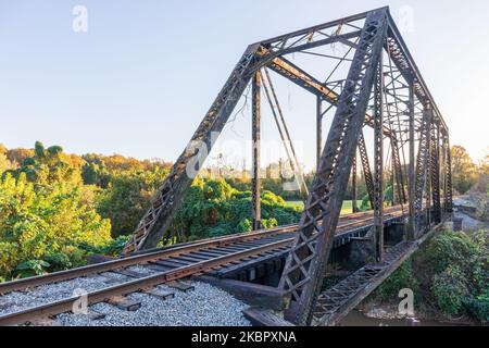 ELKIN, NORTH CAROLINA, USA-14. OKTOBER 2022: Stahlträger-Eisenbahnbrücke in der Innenstadt. Am späten Nachmittag im Frühherbst. Stockfoto